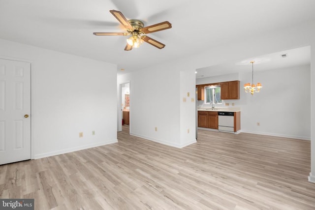unfurnished living room featuring light wood-type flooring, ceiling fan with notable chandelier, a sink, and baseboards