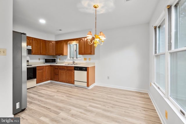 kitchen featuring a sink, light countertops, a chandelier, brown cabinetry, and stainless steel appliances