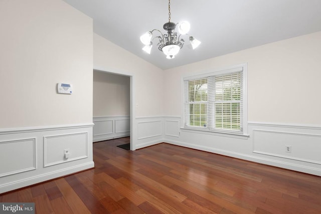 unfurnished dining area with wood finished floors, wainscoting, a chandelier, and vaulted ceiling