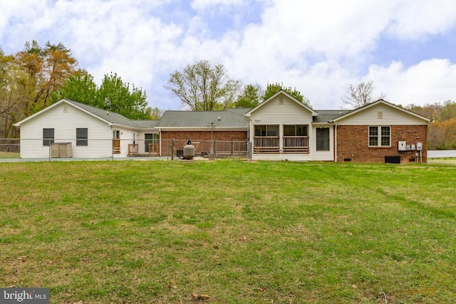 rear view of house featuring a yard, brick siding, crawl space, and fence