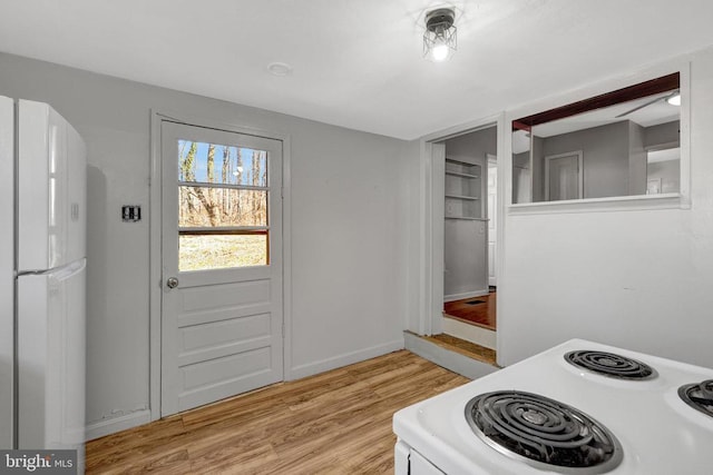 doorway to outside featuring baseboards and light wood finished floors