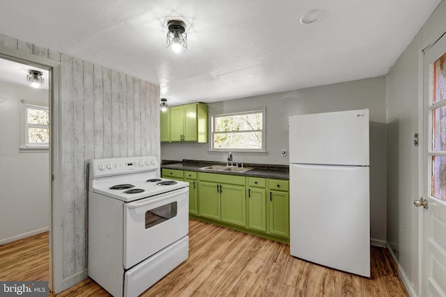 kitchen featuring dark countertops, green cabinets, light wood-style floors, white appliances, and a sink