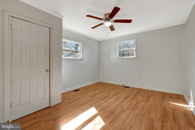 empty room with visible vents, light wood-style flooring, baseboards, and ceiling fan