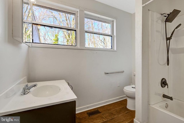 bathroom with wood finished floors, visible vents, baseboards, bathing tub / shower combination, and toilet