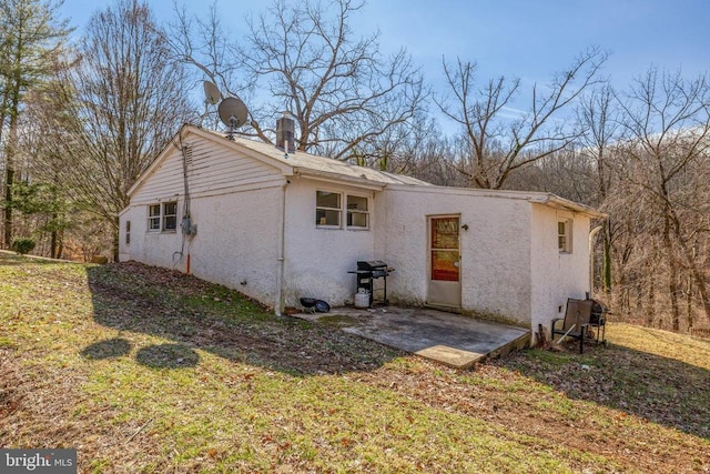 view of side of property with a patio, a yard, a chimney, and stucco siding