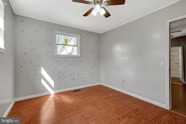 unfurnished room with visible vents, baseboards, ceiling fan, and wood finished floors