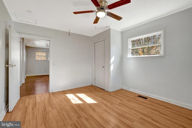 unfurnished bedroom with visible vents, crown molding, baseboards, light wood-style flooring, and a closet