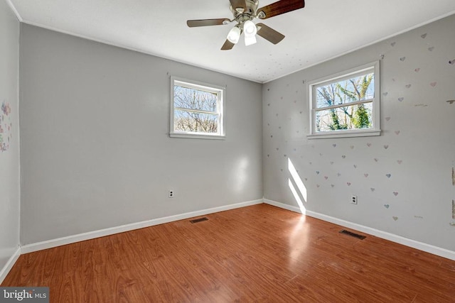 empty room featuring visible vents, a ceiling fan, baseboards, and wood finished floors