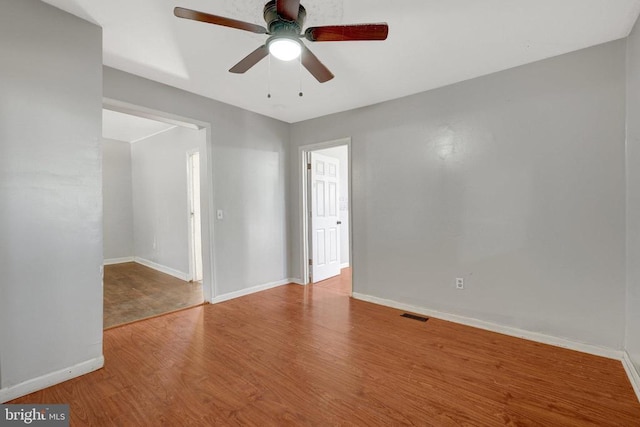 spare room with visible vents, baseboards, wood finished floors, and a ceiling fan