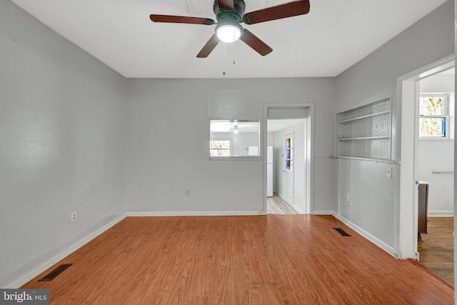 unfurnished room featuring a ceiling fan, wood finished floors, visible vents, and baseboards