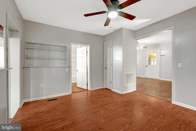 unfurnished bedroom featuring visible vents, ceiling fan, baseboards, and wood finished floors