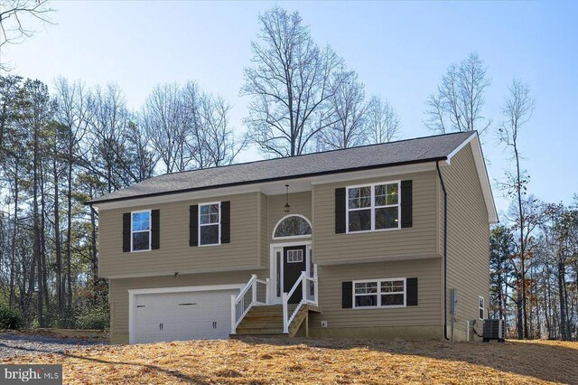 bi-level home featuring cooling unit and a garage