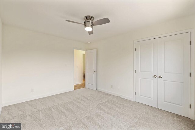 unfurnished bedroom featuring light colored carpet, ceiling fan, and a closet