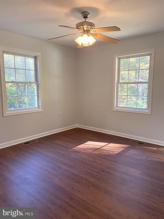 unfurnished room with ceiling fan, a healthy amount of sunlight, and dark hardwood / wood-style flooring