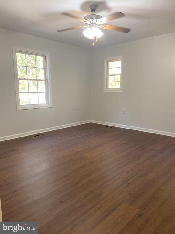 empty room featuring dark wood-type flooring and ceiling fan