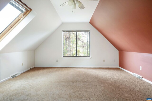 additional living space featuring lofted ceiling with skylight, carpet flooring, and ceiling fan