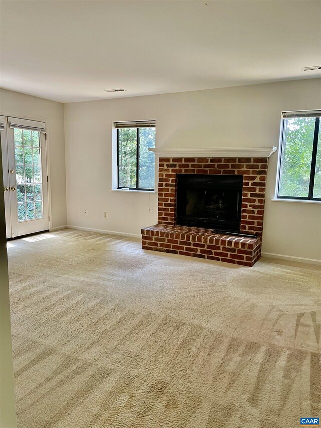 unfurnished living room with a fireplace, carpet flooring, and a wealth of natural light