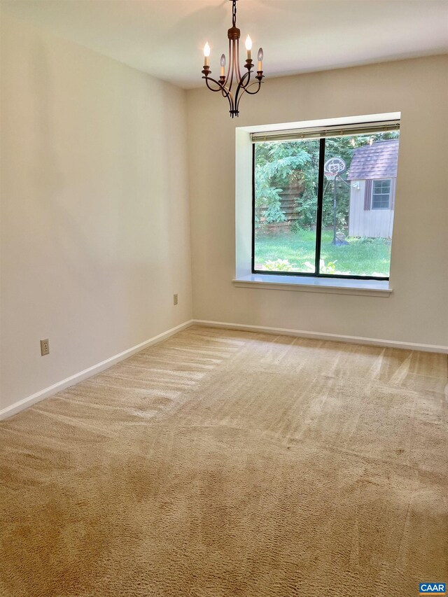 carpeted spare room featuring a notable chandelier