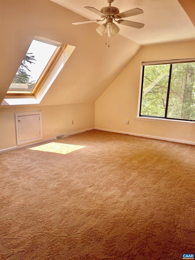 additional living space with ceiling fan, carpet flooring, and lofted ceiling with skylight