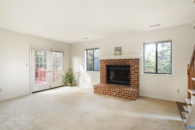 unfurnished living room with a fireplace, french doors, and carpet