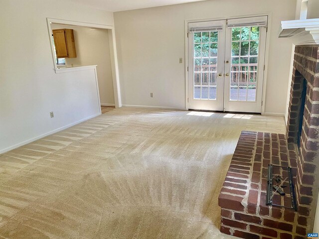 unfurnished living room featuring light colored carpet, a fireplace, and french doors