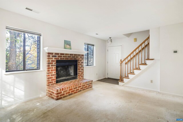 unfurnished living room featuring a brick fireplace and carpet floors