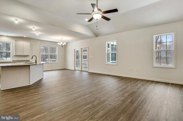 unfurnished living room with ceiling fan with notable chandelier, lofted ceiling, dark hardwood / wood-style flooring, and sink