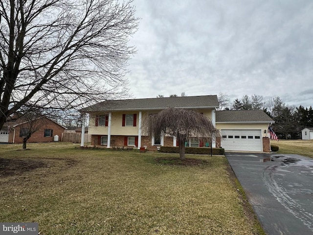 split foyer home with driveway, a garage, a front yard, and brick siding