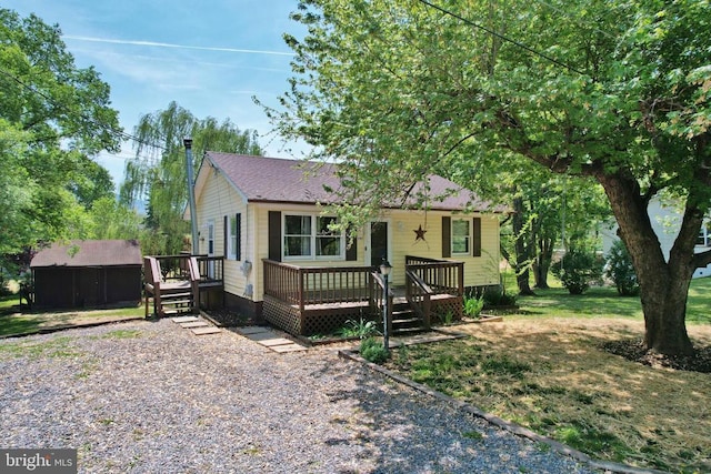 view of front of home featuring a storage shed, an outdoor structure, a deck, and a front yard