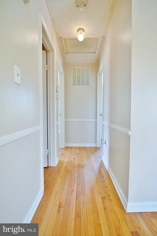 hallway with visible vents, attic access, light wood finished floors, and baseboards