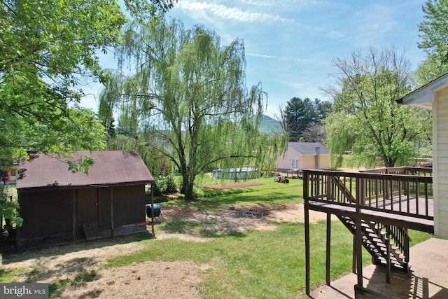 view of yard featuring a shed, a wooden deck, an outbuilding, and stairway