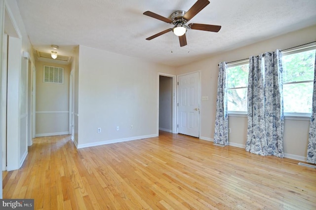 empty room with a ceiling fan, baseboards, visible vents, and wood finished floors