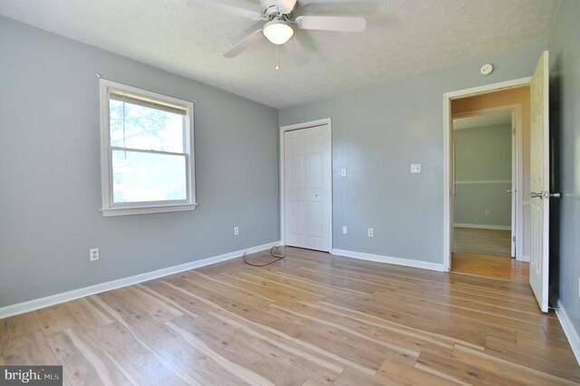 unfurnished bedroom with light wood-style floors, baseboards, and a textured ceiling