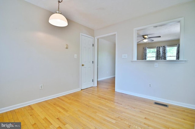 unfurnished room featuring visible vents, a ceiling fan, baseboards, and wood finished floors