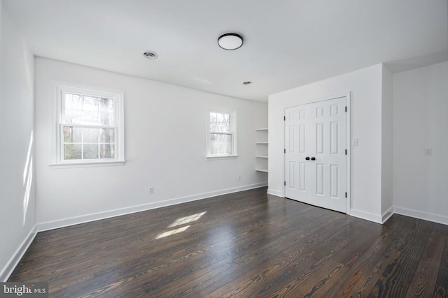 unfurnished bedroom with dark wood-type flooring, a closet, and baseboards