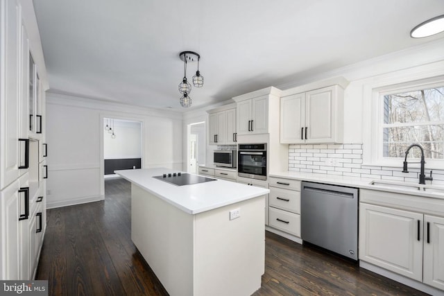 kitchen featuring decorative backsplash, a kitchen island, appliances with stainless steel finishes, light countertops, and a sink