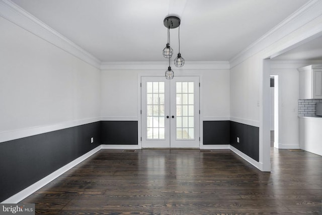 unfurnished dining area featuring baseboards, dark wood finished floors, crown molding, and french doors