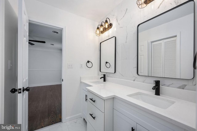 bathroom with marble finish floor, a sink, baseboards, and double vanity