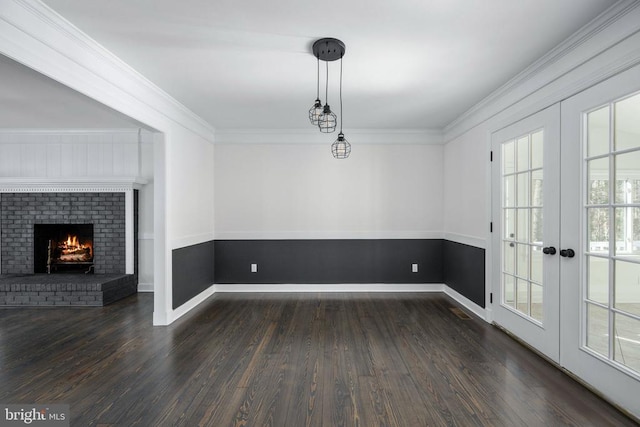 unfurnished dining area with french doors, ornamental molding, a brick fireplace, wood finished floors, and baseboards