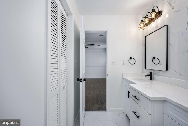 bathroom with marble finish floor, baseboards, a closet, and vanity