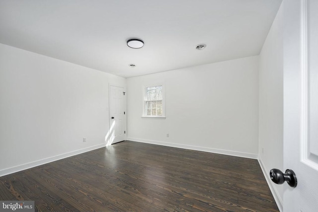 unfurnished room featuring dark wood-type flooring and baseboards