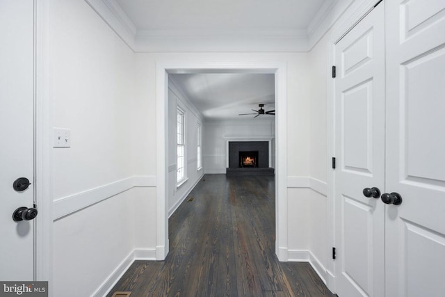 hall featuring baseboards, dark wood finished floors, and crown molding