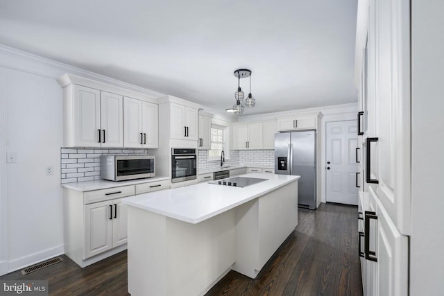 kitchen with visible vents, white cabinets, a kitchen island, appliances with stainless steel finishes, and a sink