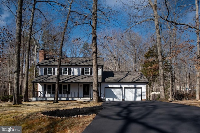 view of front of home featuring aphalt driveway, covered porch, a chimney, and a garage