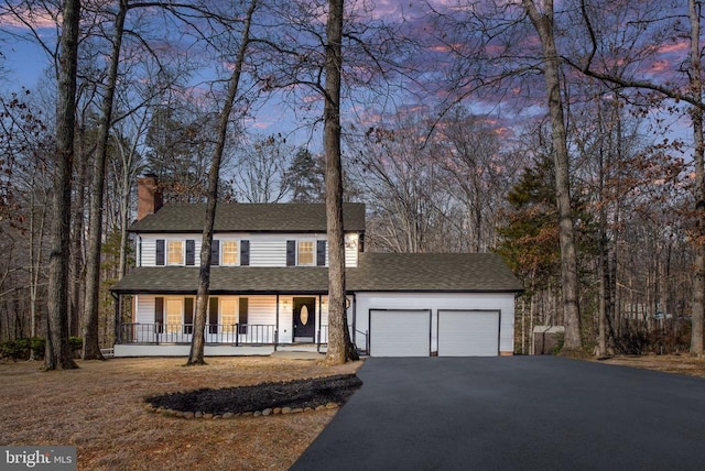 view of front of home featuring aphalt driveway, covered porch, a garage, a shingled roof, and a chimney