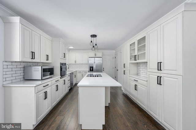 kitchen featuring appliances with stainless steel finishes, dark wood-style flooring, a center island, and white cabinets