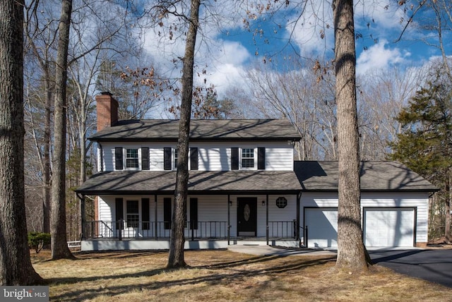 view of front of property featuring a chimney, aphalt driveway, an attached garage, covered porch, and a front lawn