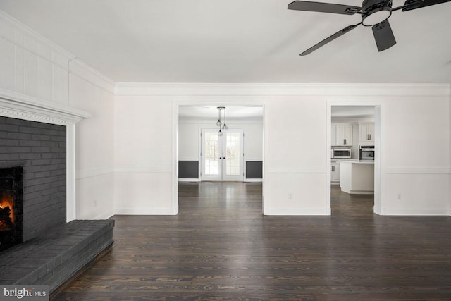 unfurnished living room featuring ceiling fan, ornamental molding, dark wood-style flooring, and a brick fireplace