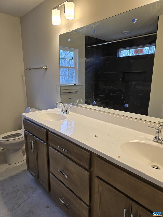 bathroom with vanity, a wealth of natural light, toilet, and a tile shower