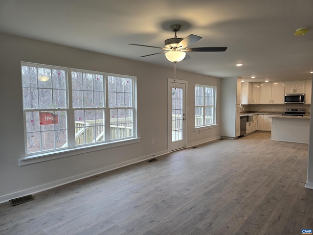 unfurnished living room with ceiling fan and light hardwood / wood-style flooring